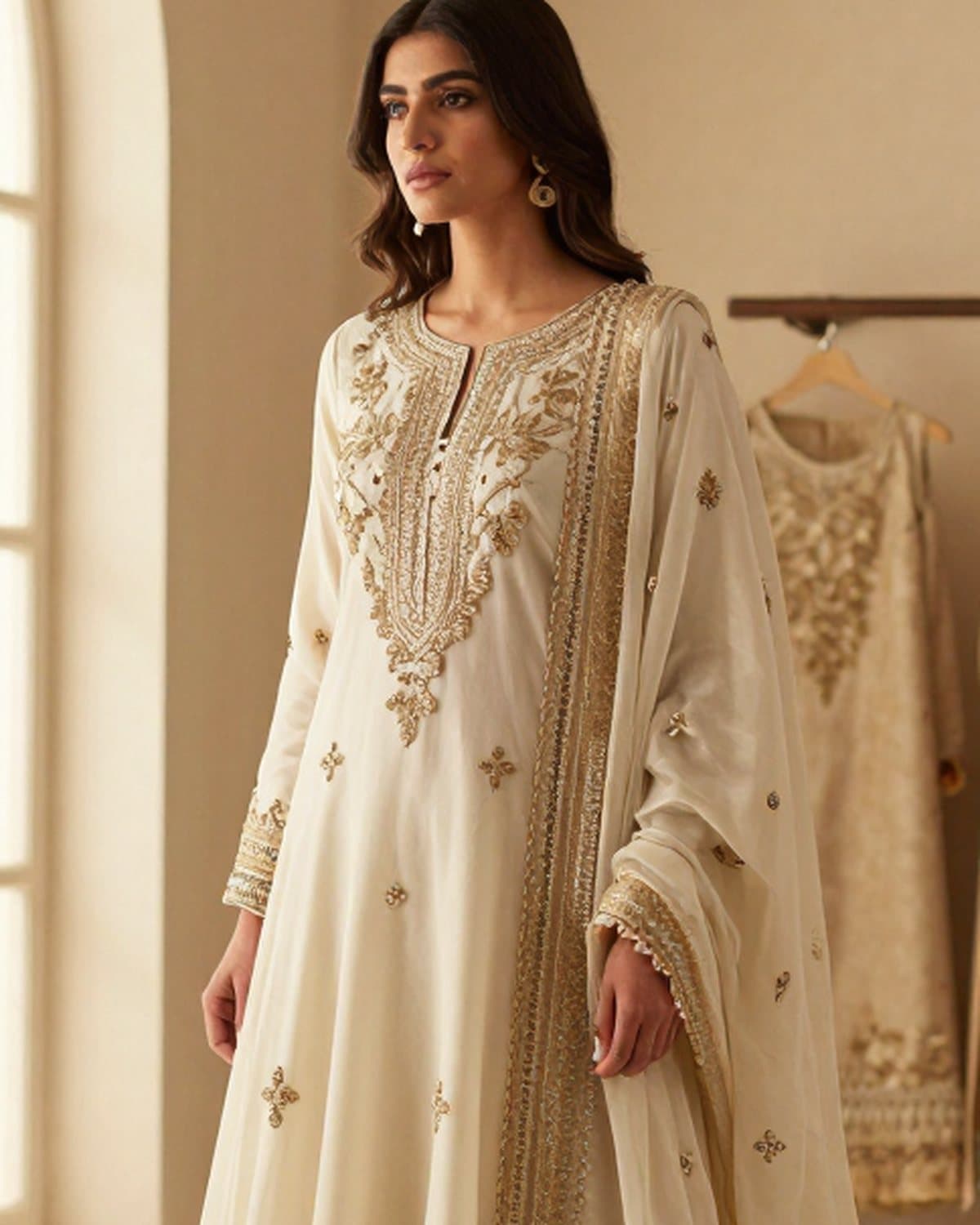 Gold work framing the neckline of an ivory anarkali